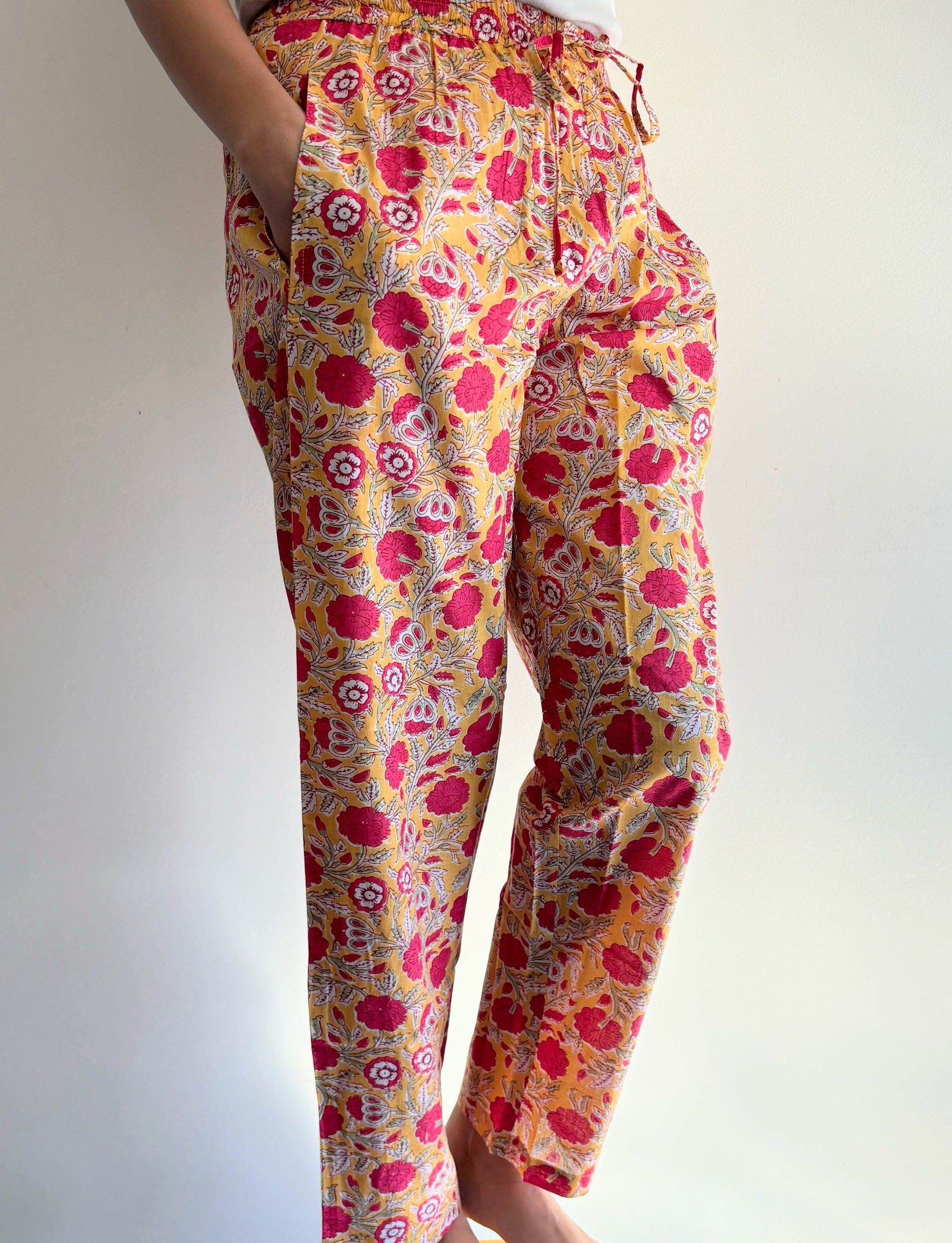 Cozy women's 100% cotton pajama pants with a pink floral design on a yellow background. These pants feature pockets, making them perfect for lounging or relaxing.