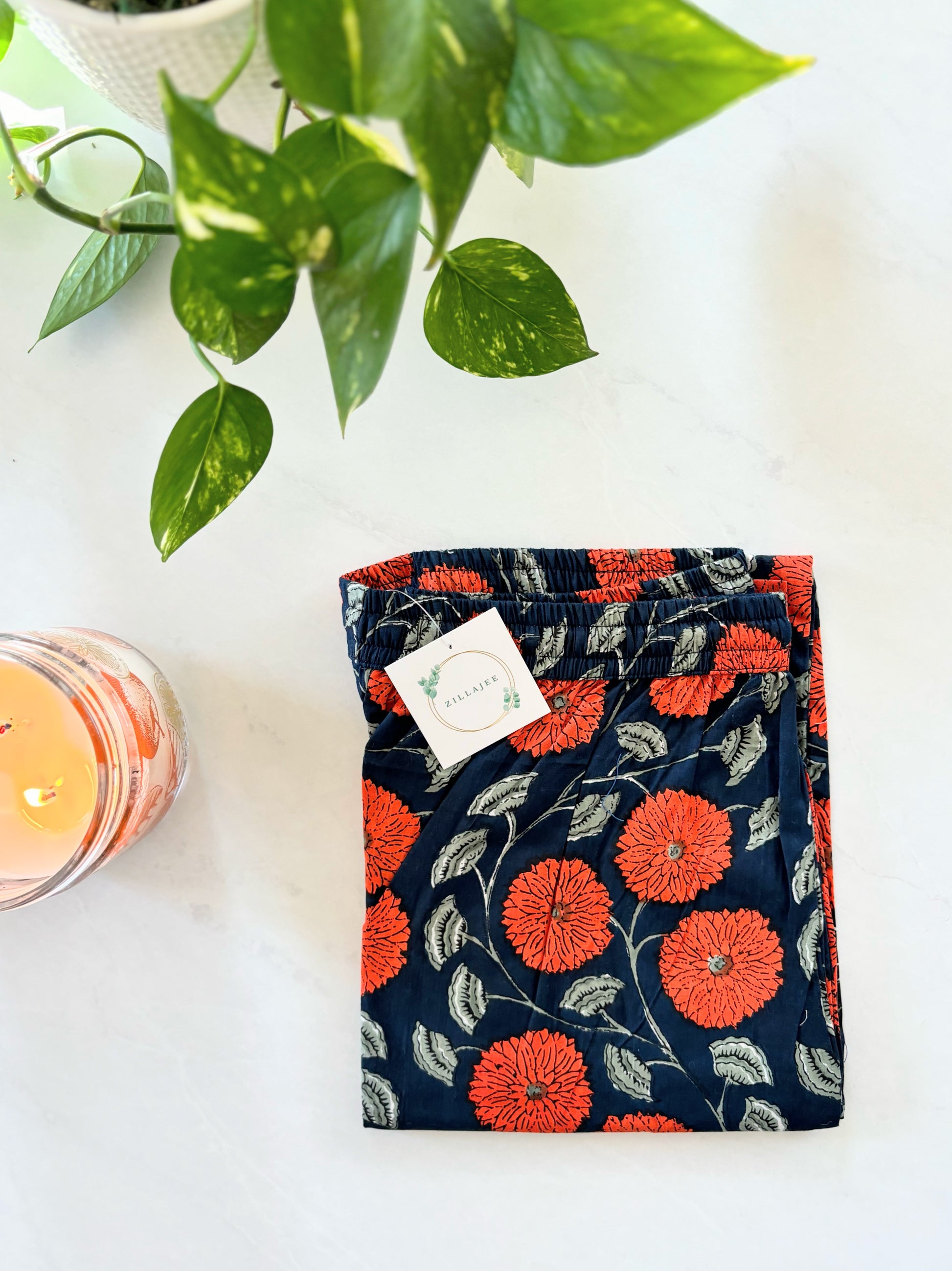 This 2-pack of women’s cotton pajama pants includes a pair with vibrant red flowers on yellow and a second pair with orange flowers on a rich navy blue background, both featuring pockets and elastic waists.