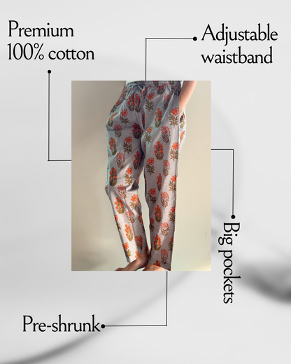 Handmade, lightweight pajama pants with pockets, perfect for lounging at home, featuring a colorful orange flower print on gray fabric for a chic, tropical look.