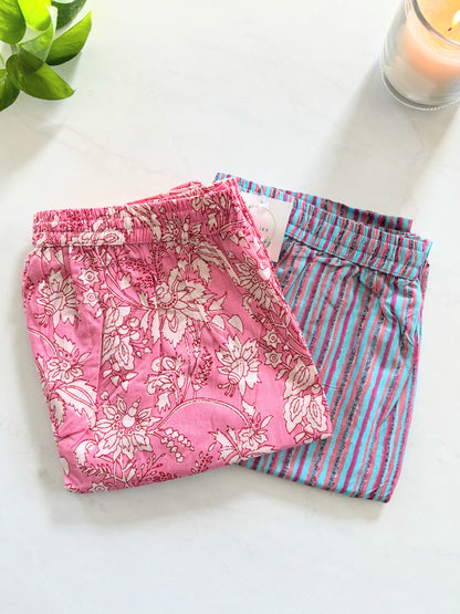 Two-pack of women’s 100% cotton pajama pants: one pair with white flowers on a pink background, and the other with pink and blue stripes, both with pockets and elastic waist.