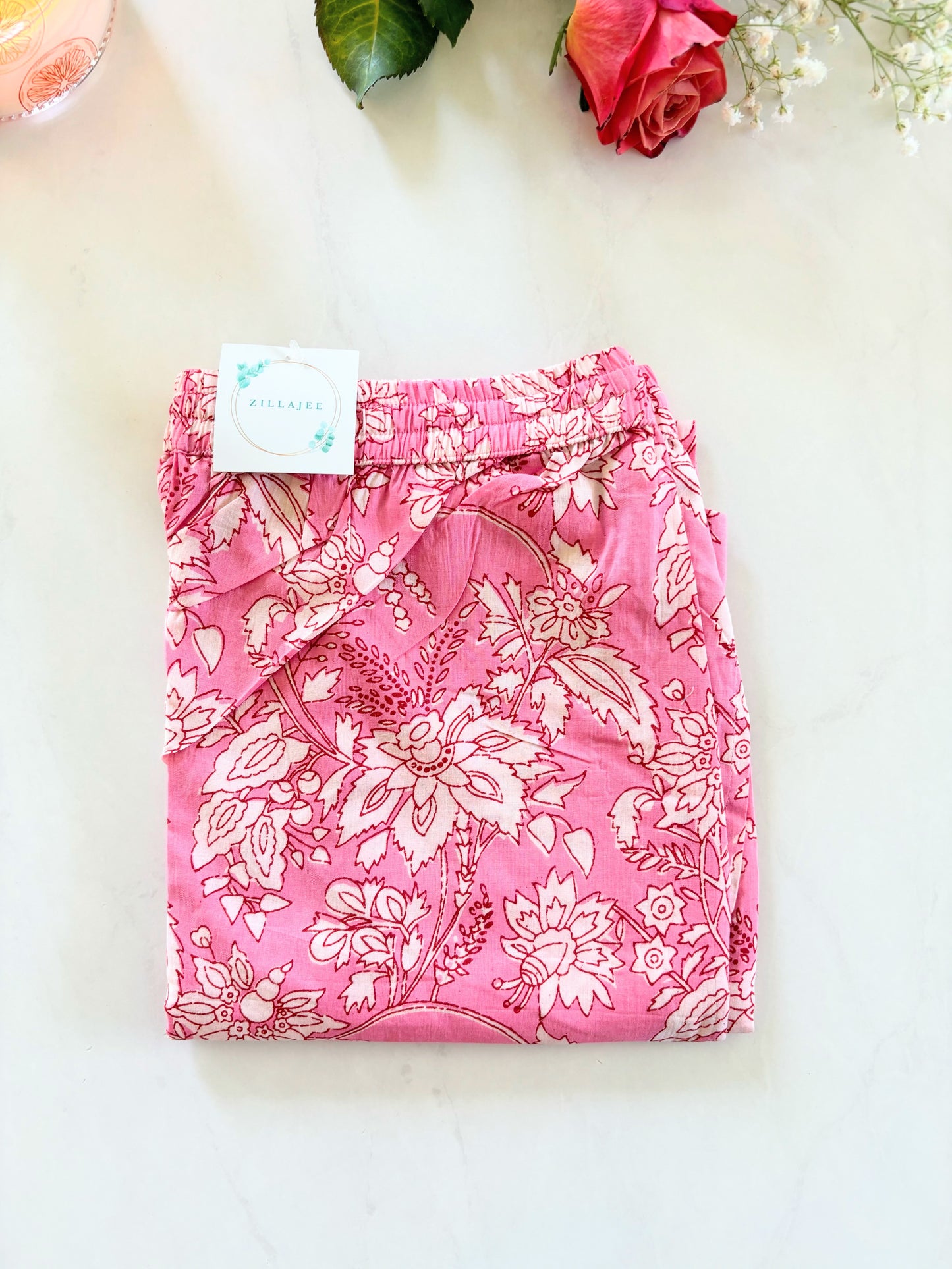 Set of two cotton pajama pants for women: one pair with delicate white flowers on pink, and another with casual pink and blue stripes, both featuring an elastic waistband and side pockets.