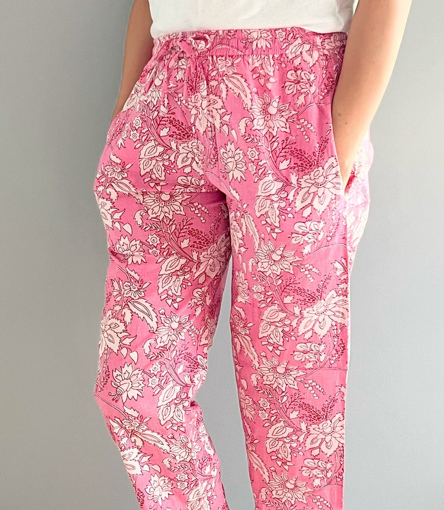 Women’s 2-pack cotton pajama pants, one pair featuring white flowers on a pink background and the other with alternating pink and blue stripes, both with elastic waistbands and pockets.